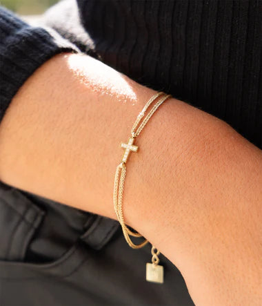 Bracelet Commissa Zag double chaîne acier doré avec croix sertie de zircons au poignet. Bijou tendance spirituel, boutique Les Tendances de Charlotte à Saint-Quentin.